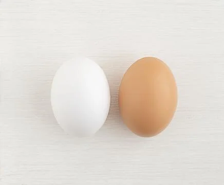 Two Easter eggs white and brown on a white wooden background, close up. copy Stock Photos