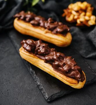 Two eclairs with dark chocolate on black board Stock Photos