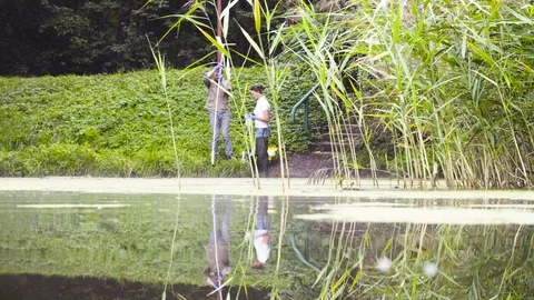 Two ecologist getting soil samples from the bottom of the lake Stockbeeldmateriaal 95382443