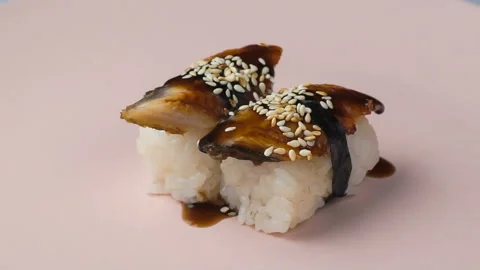 Two eel nigiri sushi spinning on the pink plate. Stock Footage 127148738