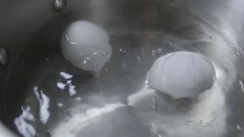 Two eggs are cooked in boiling water close-up Video stock 73103500