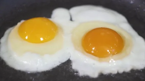 Two eggs are fried in a frying pan in oil Video stock 81269078