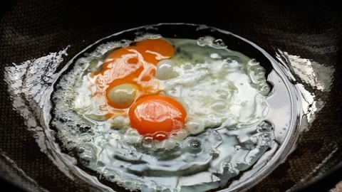 Two eggs are gradually being fried in a hot oil pan. Stock Footage 314781459