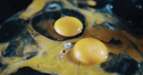 Two eggs are sitting on top of a black surface 動画素材 344907351