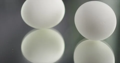 Two eggs are spinning on a mirror surface Stock Footage 197426979