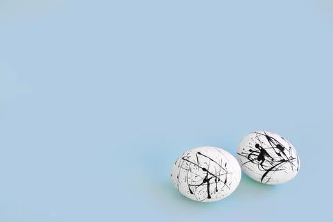 Two eggs are white with black spots on a light blue background with a copy of Stock Photos