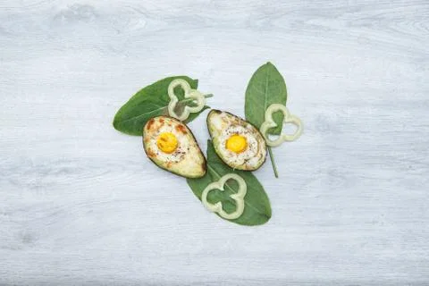 Two Eggs baked in avocado on wooden tabel and green leaves Stock Photos