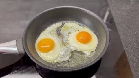 Two eggs being prepared in pan with butter Stock Footage 261061551