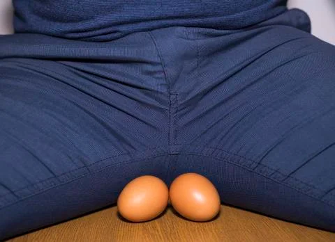 Two eggs between the legs of men - a symbol of man's balls. Stock Photos