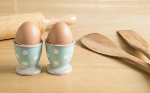 Two eggs in blue polka dot egg cups and baking utensils Stock Photos