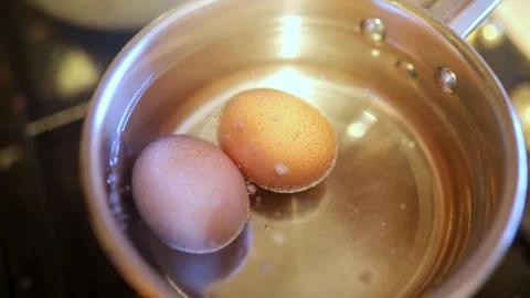 Two eggs boiling in hot water in a cooking pot on gas stove Stock Footage 317102639