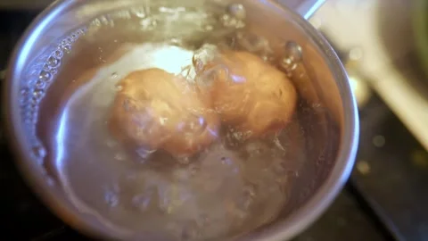 Two eggs boiling in hot water in a cooking pot on gas stove Stock Footage 317102652