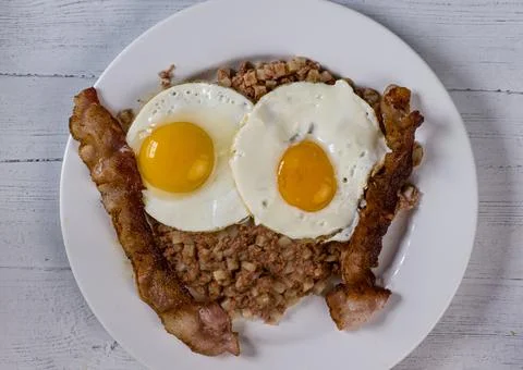 Two eggs on corn beef hash  with  a side of bacon Foto stock