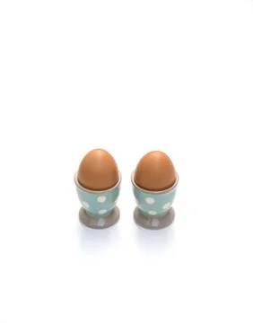 Two eggs in egg cups on white background Stock Photos