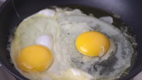 Two eggs  frying in a black pan. Stock Footage 131149799