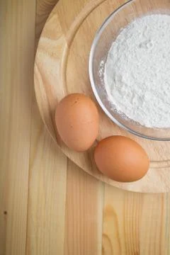 Two eggs on a round stand next to a plate of flour Stock Photos