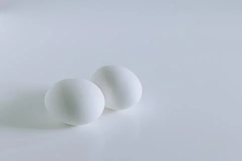 Two eggs on a white background. Minimal concept. Stock Photos