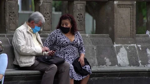 Two elder wearing face masks rest and chat Stock Footage 135192799