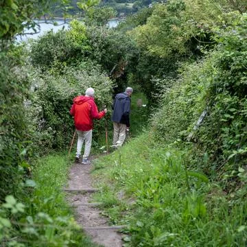 Two elderly hikers on path through green bushes near saint malo in france Stock Photos