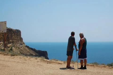 Two elderly men, disabled, stand back and talk amid the ocean. Foto stock