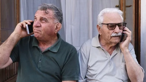Two elderly men engage in telephone conversations with their smart phones Stock Footage 80893337