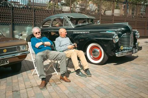 Two Elderly Men Sitting by Classic Cars at Car Boot Sale Stock Photos