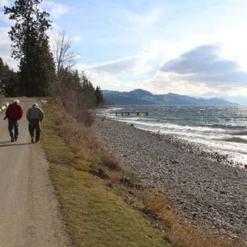 Two elderly men walking alongside of rocky beach Stock Photos