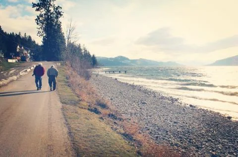 Two elderly men walking alongside of rocky beach Stock Photos