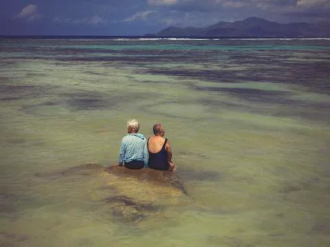 Two elderly people on a rock in the middle of the Indian Ocean Stock Photos