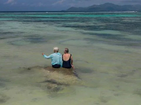 Two elderly people on a rock in the middle of the Indian Ocean Stock Photos