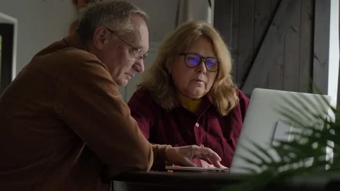 Two elderly people surfing internet on laptop computer at home. 4K video Stock Footage 161321486