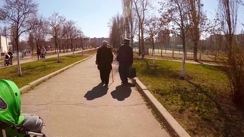 Two elderly people walk along the park avenue Stock Footage 74135231