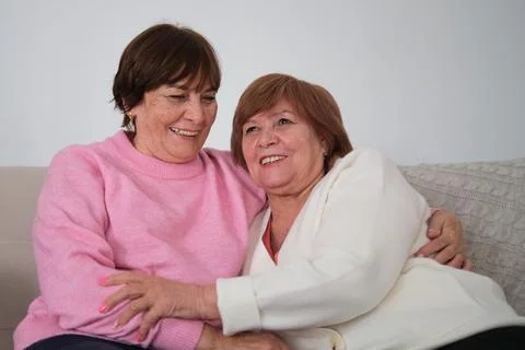 Two elderly sisters lovingly embracing each other, showcasing the enduring Foto stock