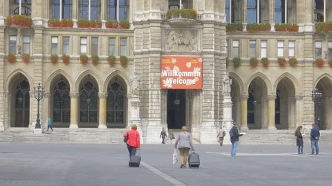 Two elderly tourists with luggage going to main entrance of Rathaus in Vienna Stock Footage 82332220