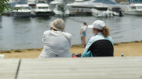 Two elderly women are sitting on a bench by the sea, gazing at the water. A.. 動画素材 344464174