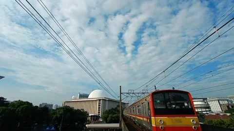Two electric commuter trains passing the white mosque in Jakarta Stock Footage 241895331