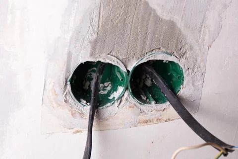 Two electrical conduit boxes are embedded in a wall, with wires protruding .. Photos