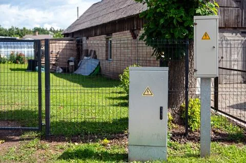 Two electrical distribution cabinets stand on a lawn next to a building and f Stock Photos