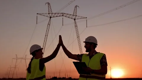 Two electrical engineers give high five against the backdrop of high-voltage Stock Footage 201032115