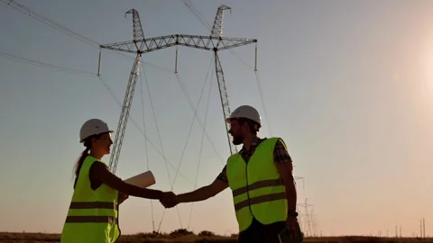 Two electrical engineers meet and shake hands against the backdrop of high 動画素材 201032130