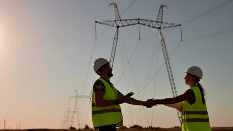 Two electrical engineers meet and shake hands against the backdrop of high 動画素材 204857760