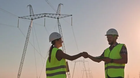 Two electrical engineers meet and shake hands against the backdrop of high Stockbeeldmateriaal 206033778