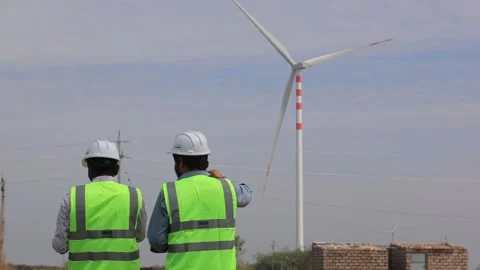 Two electrical engineers in safety vests and hard hats reviewing site plans at Stock Footage 336797404