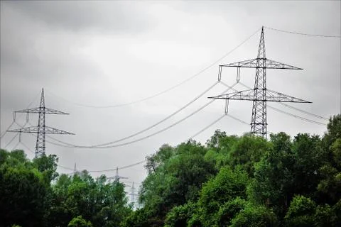 Two electrical towers behind trees Stock Photos