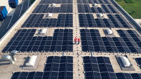 Two electricians walking on rooftop solar panel array aerial back view Stock-Footage 278670718
