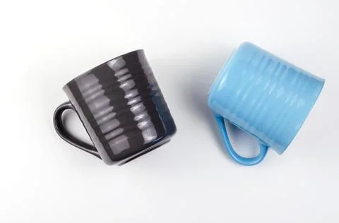Two elegant ceramic mugs on a white background. Gray and blue cups for hot dr Stock Photos