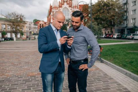 Two elegant men standing with mobile phone. Stock Photos