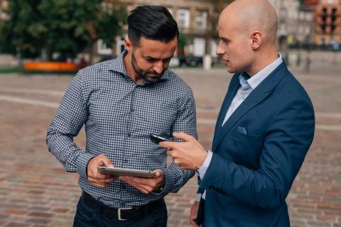 Two elegant men standing with tablet pc and mobile phone. Stock Photos