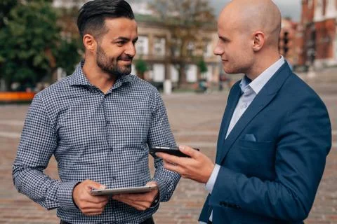 Two elegant men standing with tablet pc and mobile phone. Stock Photos