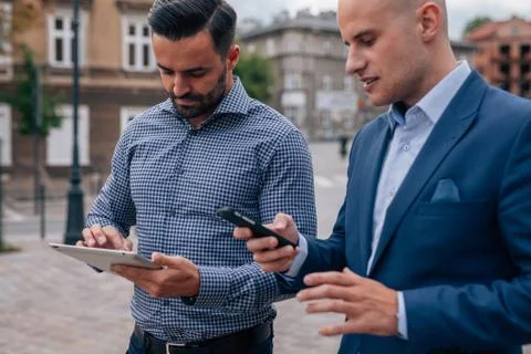 Two elegant men standing with tablet pc and mobile phone. Stock Photos